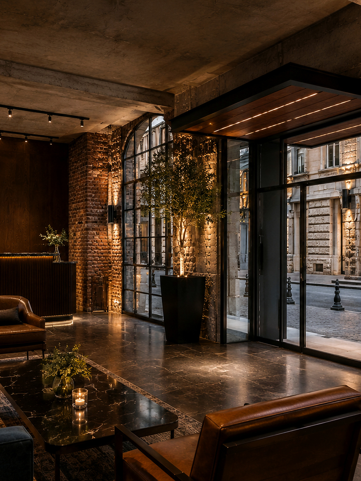 Karaköy Loft lobisinin arkasında yükselen siyah çelik merdiven ve aydınlatılmış taş duvarlar